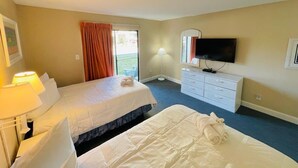 Ein Hotelzimmer mit zwei Betten, einem Fernseher, einem Schreibtisch mit Lampe und einem Schminktisch.