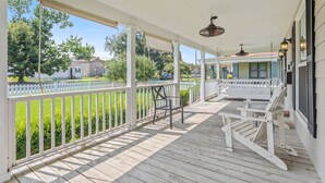 A covered porch with white railings, a bench, and a rocking chair.
