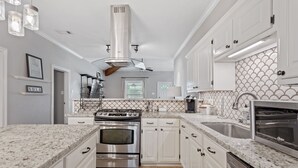 A modern kitchen with white cabinetry, granite countertops, stainless steel appliances, and a decorative backsplash.