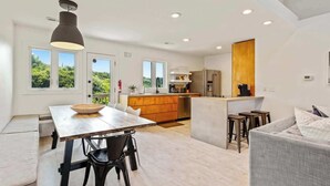 A modern kitchen with a central island, a dining area with a table and chairs, and a living area with a sofa. - Modern Coastal Home, Close to Beach with Pool, Spa (Kitty Hawk)