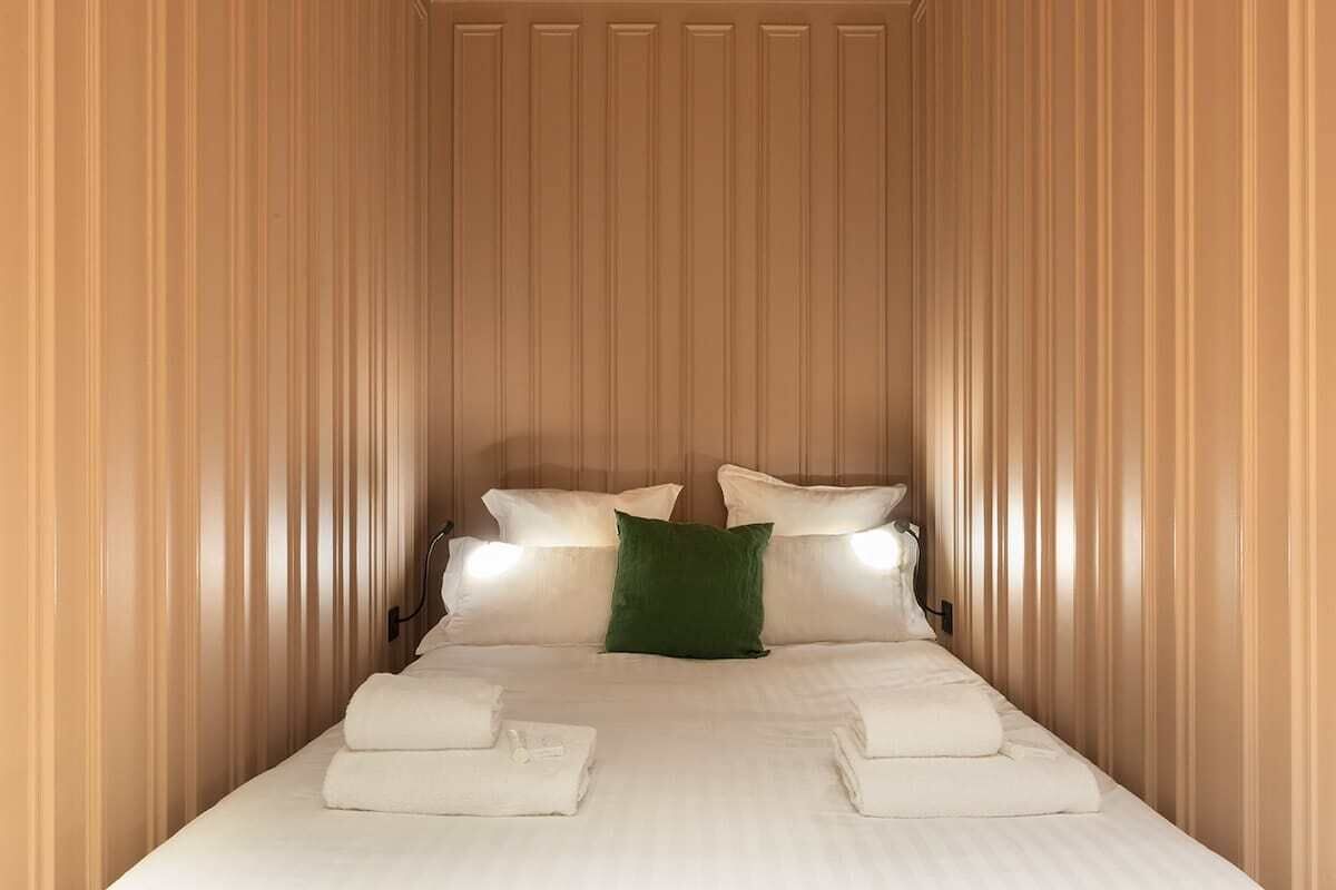Une chambre d’hôtel avec un lit, des oreillers et un coussin décoratif vert.
