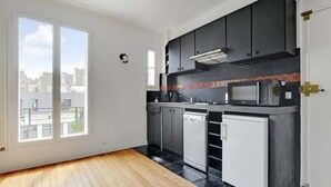 A modern kitchen with dark cabinets, a microwave, and a dishwasher. - An Amazing 2-BR/1BA in Ternes - Arc de Triomphe (Paris)