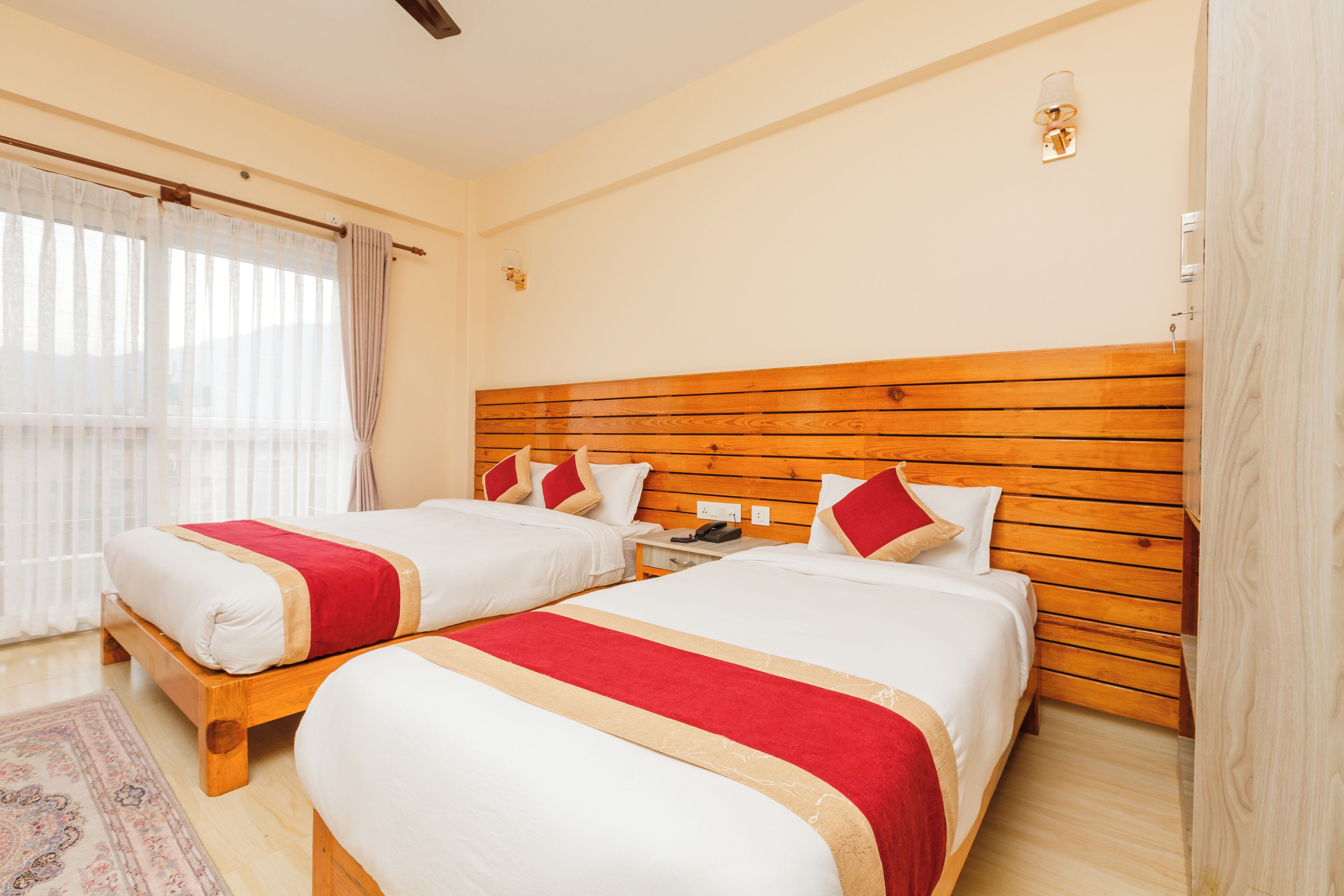 A hotel room with two beds, wooden headboards, and a small bedside table.