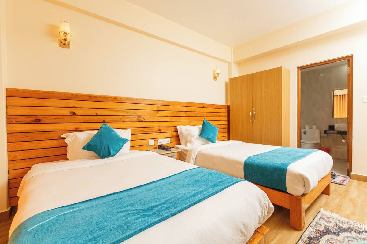 A hotel room with two beds, wooden headboards, and a wardrobe.