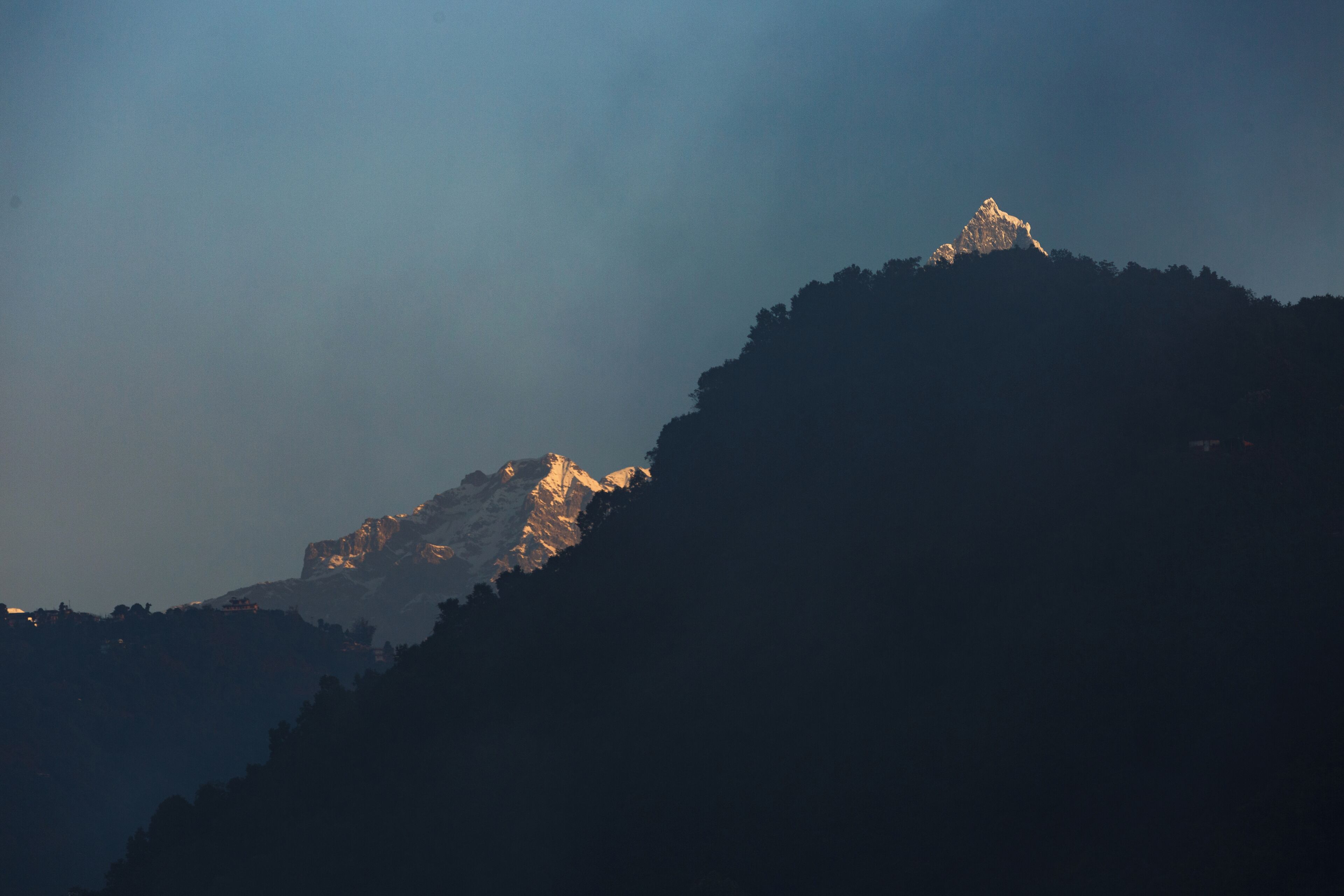 Ein Berg mit einer sonnendurchfluteten Spitze, umgeben von bewaldeten Hängen.
