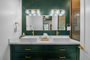 A bathroom with two sinks, a large mirror, and green cabinets. - Luxury Home with Lake Views, Hot Tub, AC, Game Room & Walk to Village (Big Bear Lake)