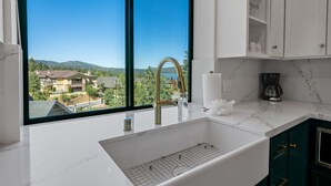 Eine moderne Küche mit großem Fenster, weißen Schränken und einer Marmarbeitebene.