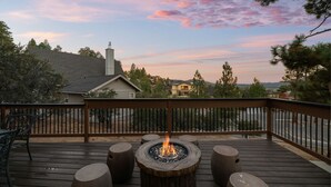 Eine Terrasse mit Feuerstelle, Sitzgelegenheiten und Blick auf die umliegende Landschaft.