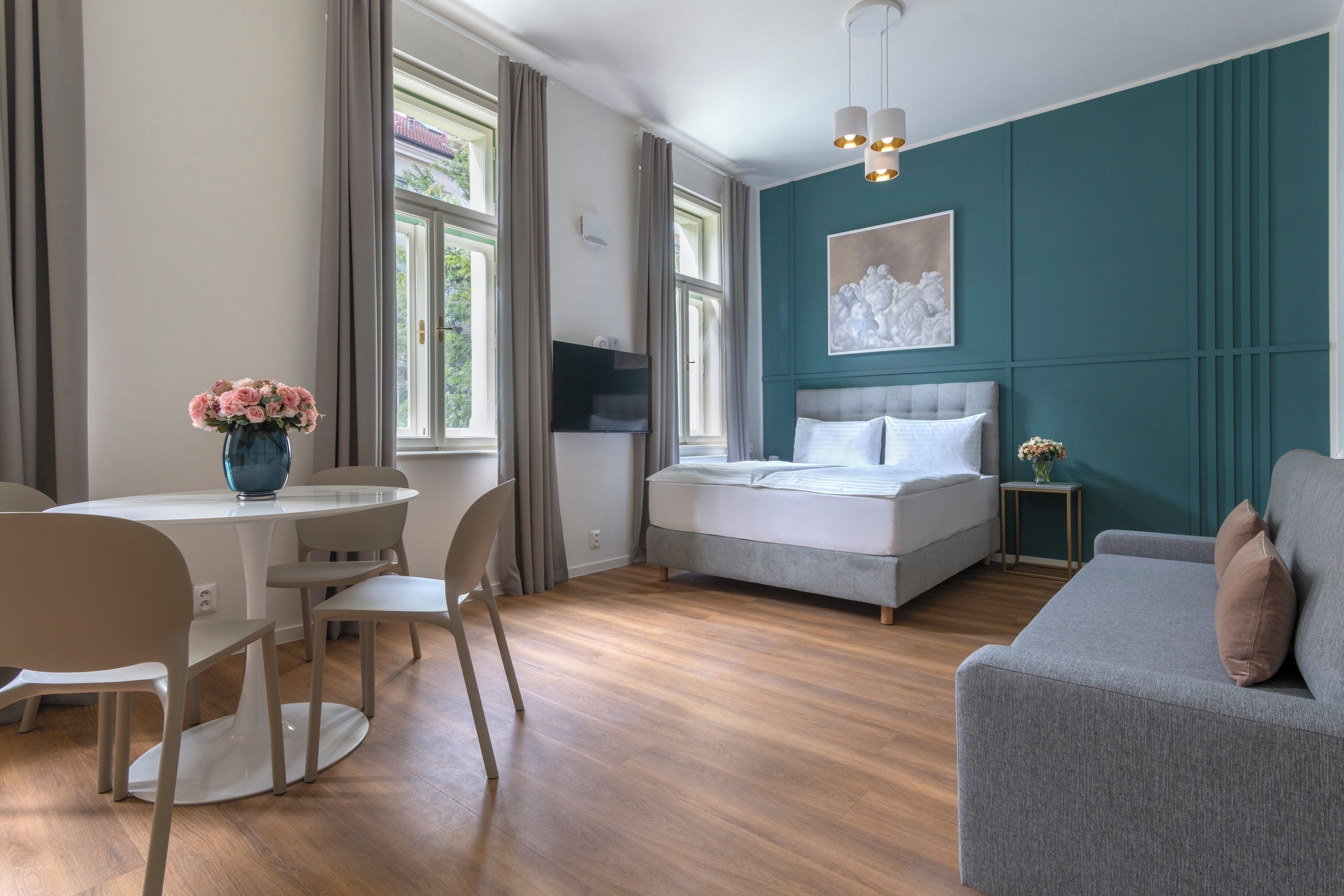 Een moderne slaapkamer met een bed, een zithoek met een bank, een eettafel met stoelen en een televisie.