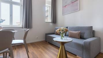 Una sala de estar moderna con un sofá gris, una mesa redonda con base dorada y un florero con flores.