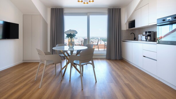 A modern kitchen with a dining area, large windows, and a city view. - Encore Boutique Residence by Dwellfort (Prague)
