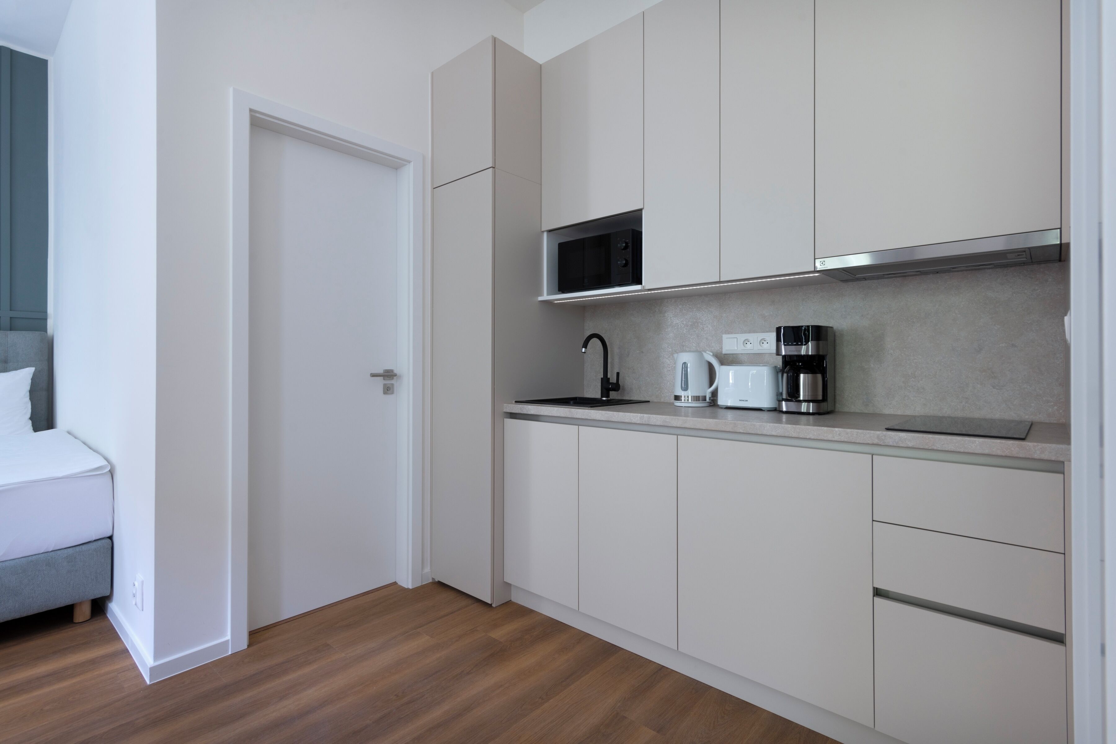 A modern kitchen with white cabinets, a microwave, a coffee maker, and a toaster.