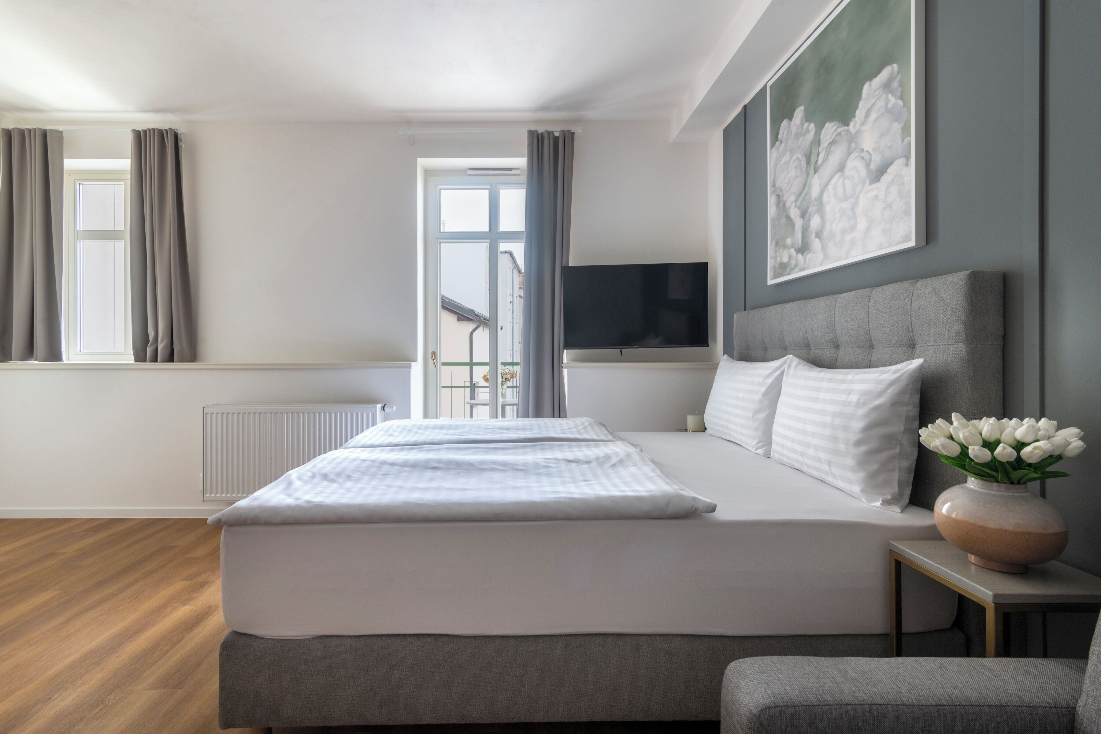 Una camera da letto moderna con un letto grande, una televisione a schermo piatto, un quadro e vista sull'esterno.