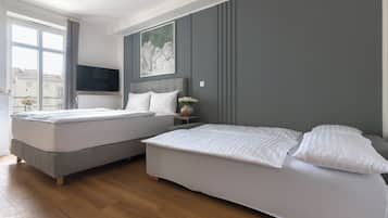 A modern hotel room with two beds, a flat-screen TV, a painting, and a window with a view of buildings.