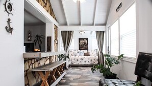 Un salón acogedor con una pared de piedra, un banco de madera, un sillón de cuero negro y un sofá estampado.