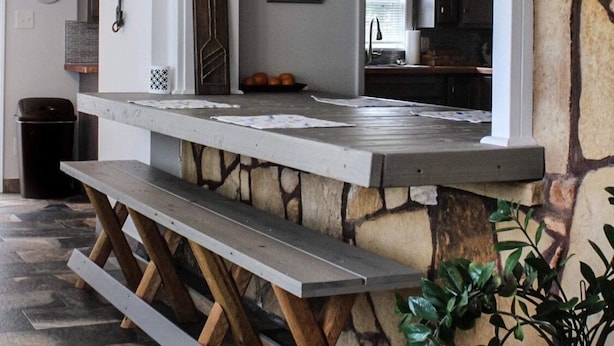 Un área de cocina con pared de piedra, un banco de madera y una pizarra con decoración náutica.