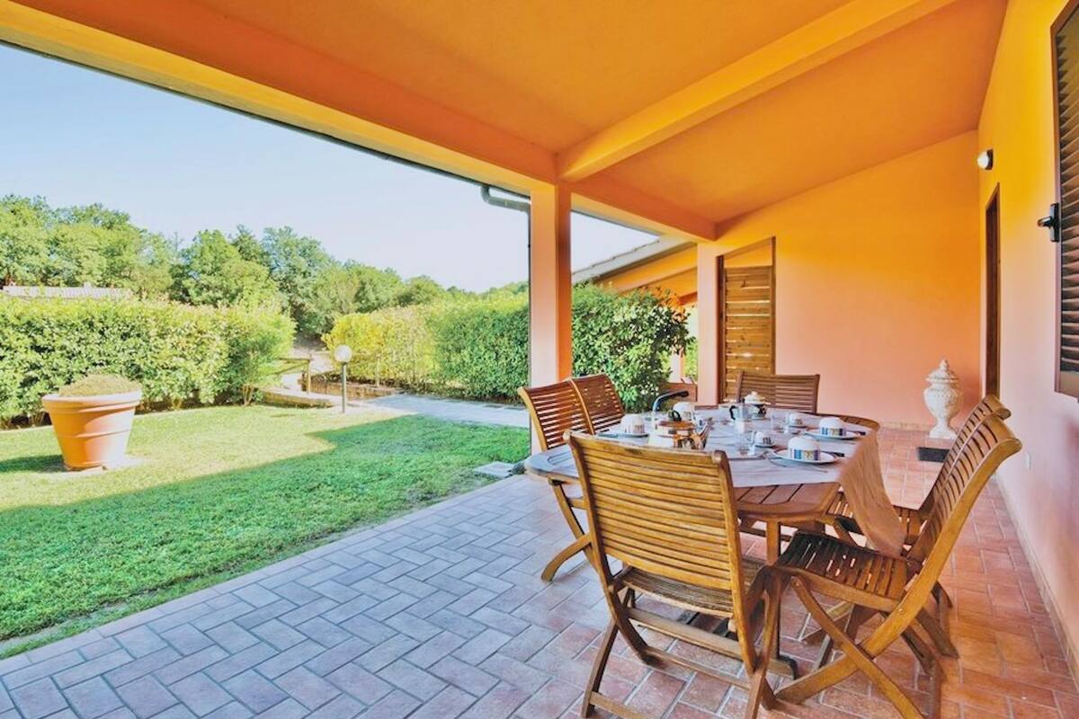 Un patio al aire libre con una mesa y sillas, una planta en maceta y vistas a un jardín.