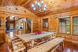 L’intérieur d’un chalet rustique en bois, avec une table à manger, des bancs et un lustre.