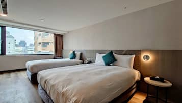A hotel room with two beds, a view of the city, and a small table with a phone and tissues.