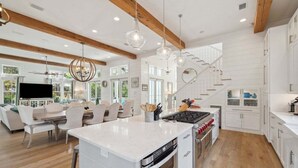 A spacious kitchen with a central island, wooden beams, and pendant lighting. - Next to Camp WaterColor! Sleeps 22! Pool, Gym, LSV, Bikes & Carriage House! (Santa Rosa Beach)