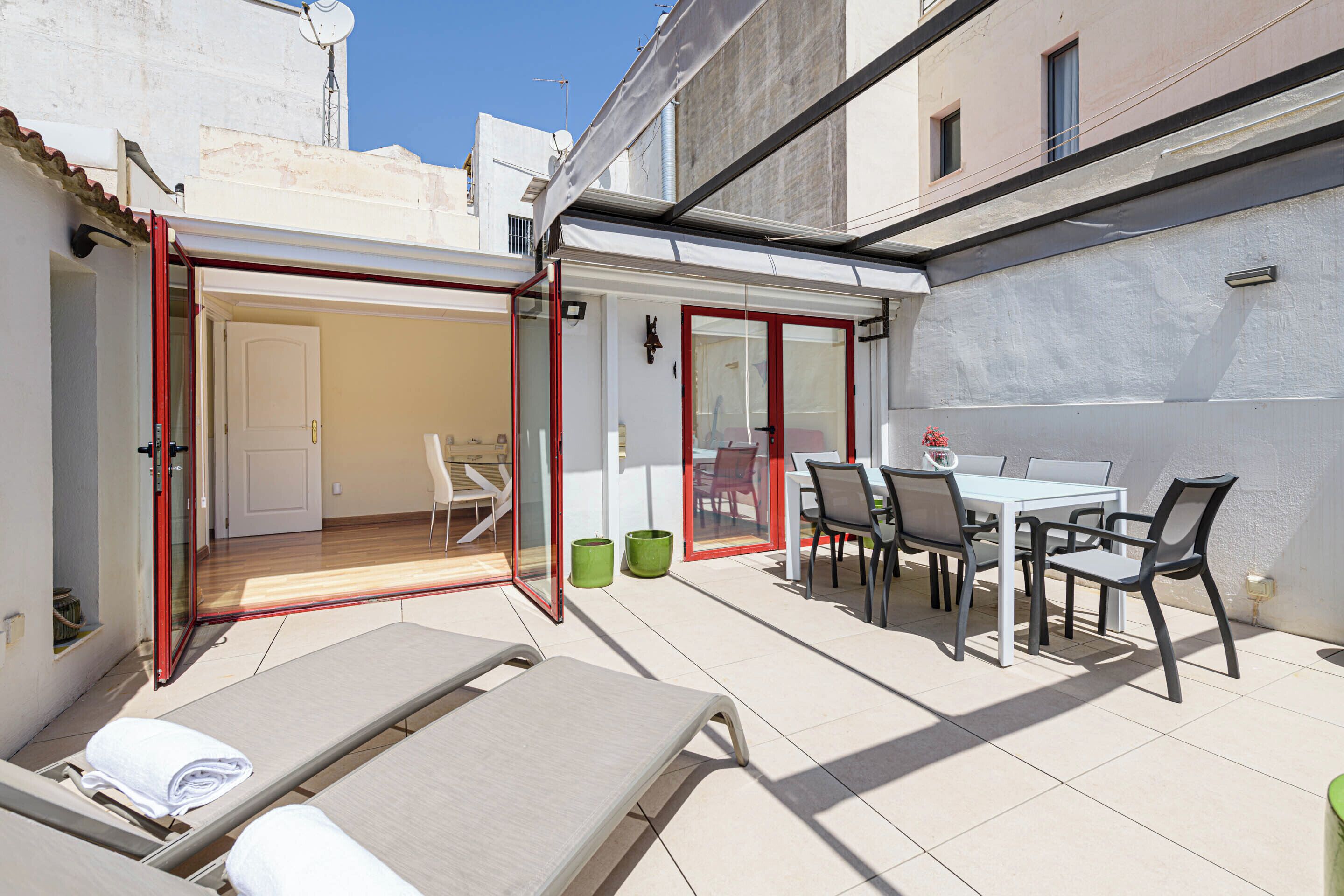 A sunlit patio with lounge chairs, a dining table, and chairs.