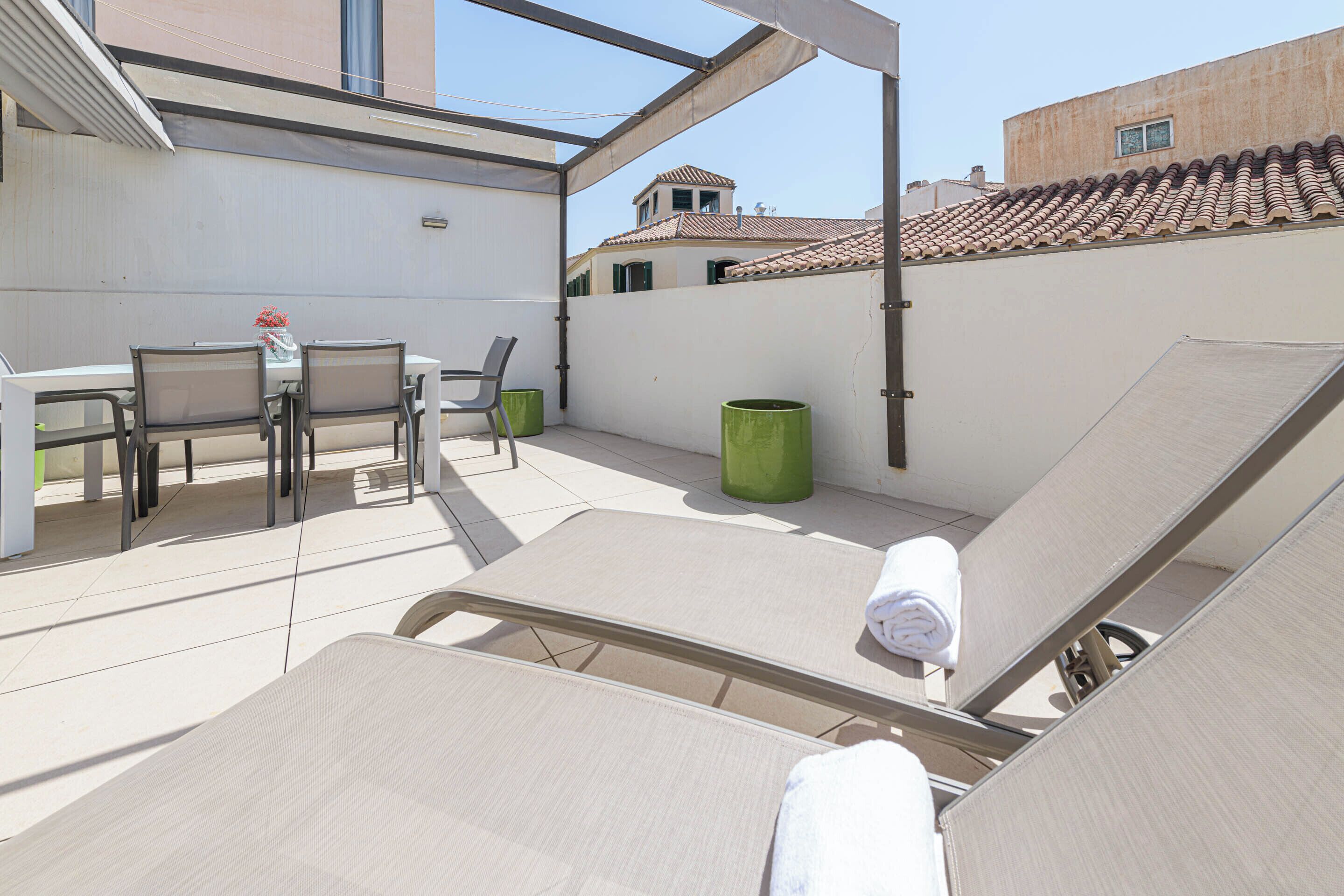 A rooftop terrace with lounge chairs, a table, and chairs.