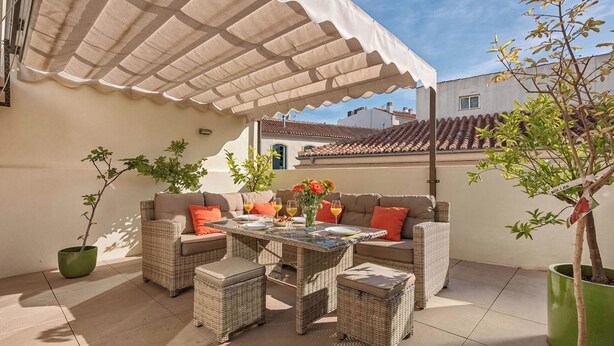 An outdoor patio area with wicker furniture, a table with drinks, and potted plants. - Solaga - Emma (Málaga)