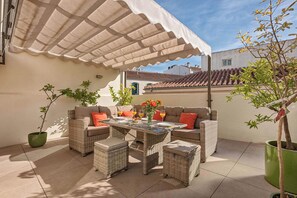An outdoor patio area with wicker furniture, a table with drinks, and potted plants. - Solaga - Emma (Málaga)