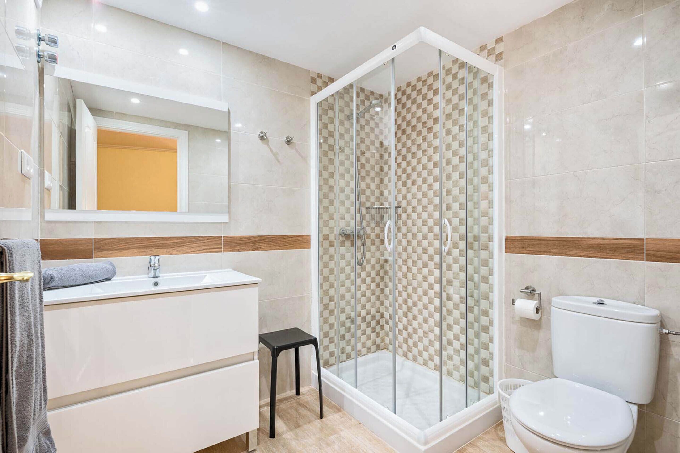Ein modernes Badezimmer mit einer Duschkabine, einem weißen Waschbecken und einer Toilette.
