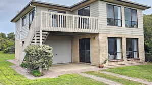 Une maison à deux étages avec un balcon, un garage et un petit jardin.