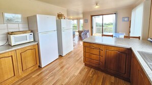 Une cuisine avec des meubles en bois, un réfrigérateur blanc, un four à micro-ondes et un grand îlot central.