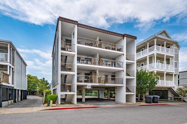 A multi-story residential building with balconies, a garage, and a clear sky.