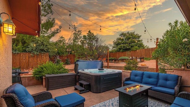 An outdoor patio with a hot tub, seating area, and string lights. - Sedona RedRock Retreat | Hot Tub, Fire Pit & Views (Sedona)