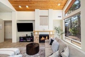 A living room with a fireplace, a large TV, and a sofa.