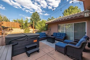 An outdoor patio with a grill, blue sofas, and wicker furniture.