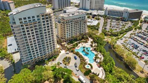 A high-rise hotel with multiple floors, a swimming pool, and a parking area. - Best views and close to the beach! 7801 L1 (Miramar Beach)