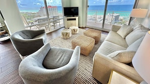 A spacious living room with a large flat-screen TV, comfortable seating, and a balcony with a view of the ocean. - Best views and close to the beach! 7801 L1 (Miramar Beach)