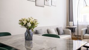 Un salon moderne avec une table basse en marbre, un vase de fleurs blanches, un canapé gris et une lampe sur pied.