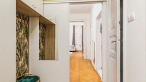Un couloir doté d’un parquet en bois disposé en chevrons, d’un banc recouvert d’un tissu vert et d’une porte donnant sur une autre pièce.