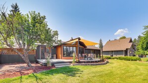 A modern house with a patio, a small deck, and a well-maintained lawn. - Deck & Mtn Views: Libby Home on Golf Course! (Libby)