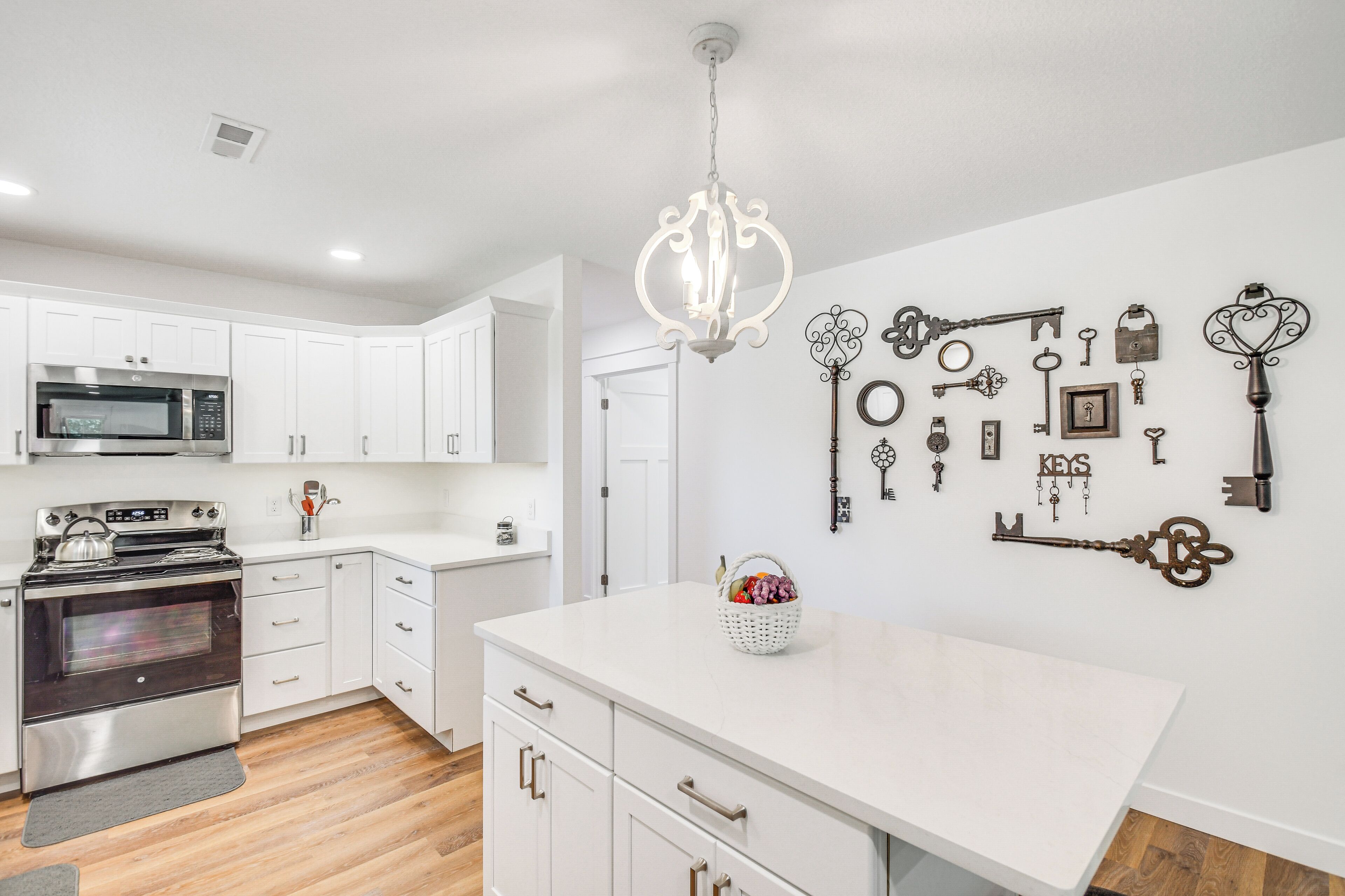 A modern kitchen with white cabinetry, a stainless steel oven, and a microwave.