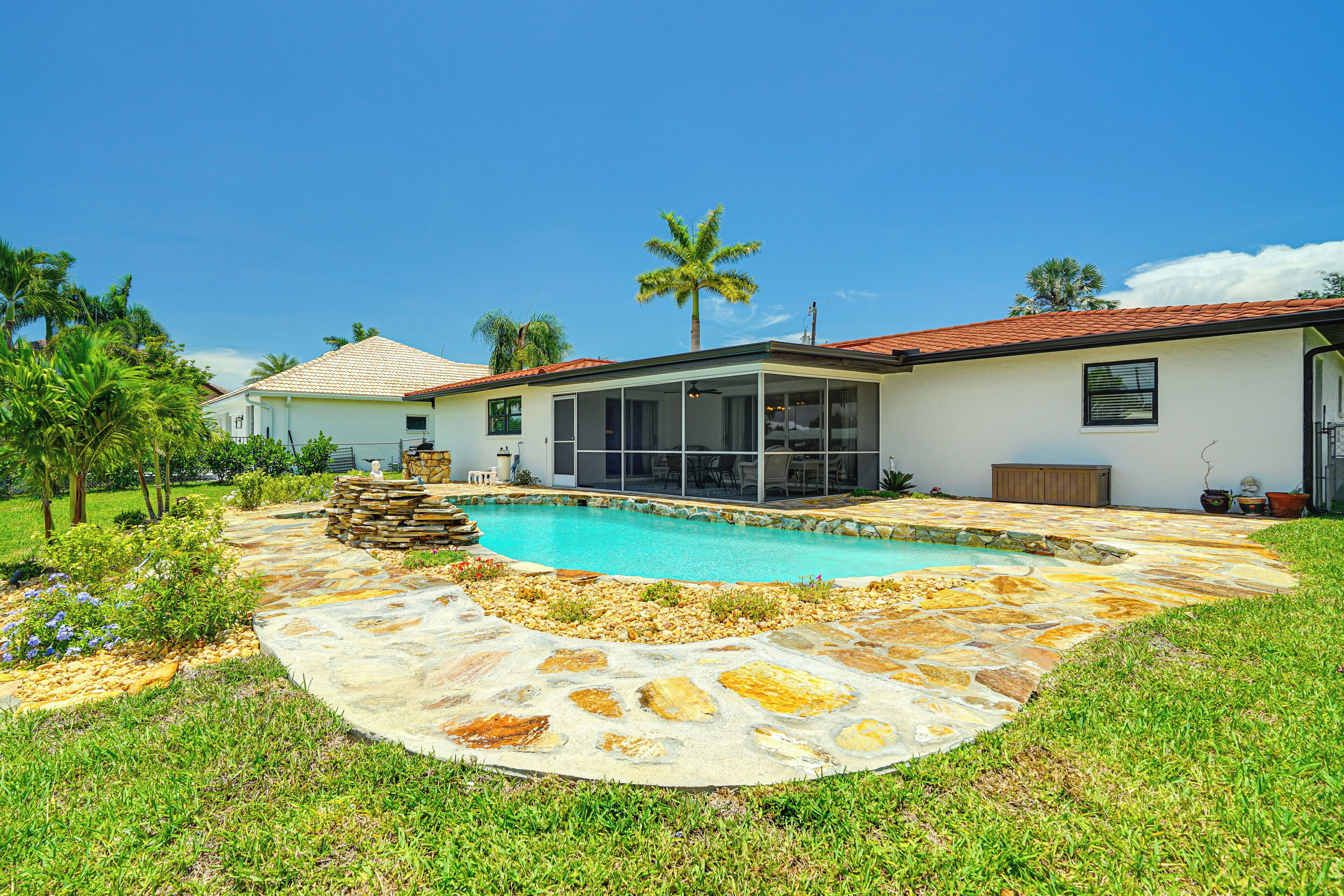 Una casa con piscina, patio de piedra y césped bien cuidado.
