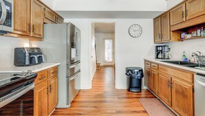Une cuisine moderne avec des meubles en bois, des appareils électroménagers en acier inoxydable et une horloge au mur.