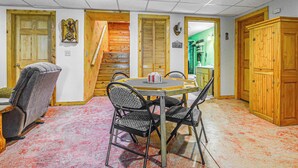 A dining area with a wooden table and chairs, a staircase, and a green room in the background. - Peaceful Wautoma Retreat w/ Deck on 10 Acres! (Wautoma)