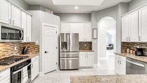 Una cocina moderna con armarios blancos, electrodomésticos de acero inoxidable y encimera de granito.
