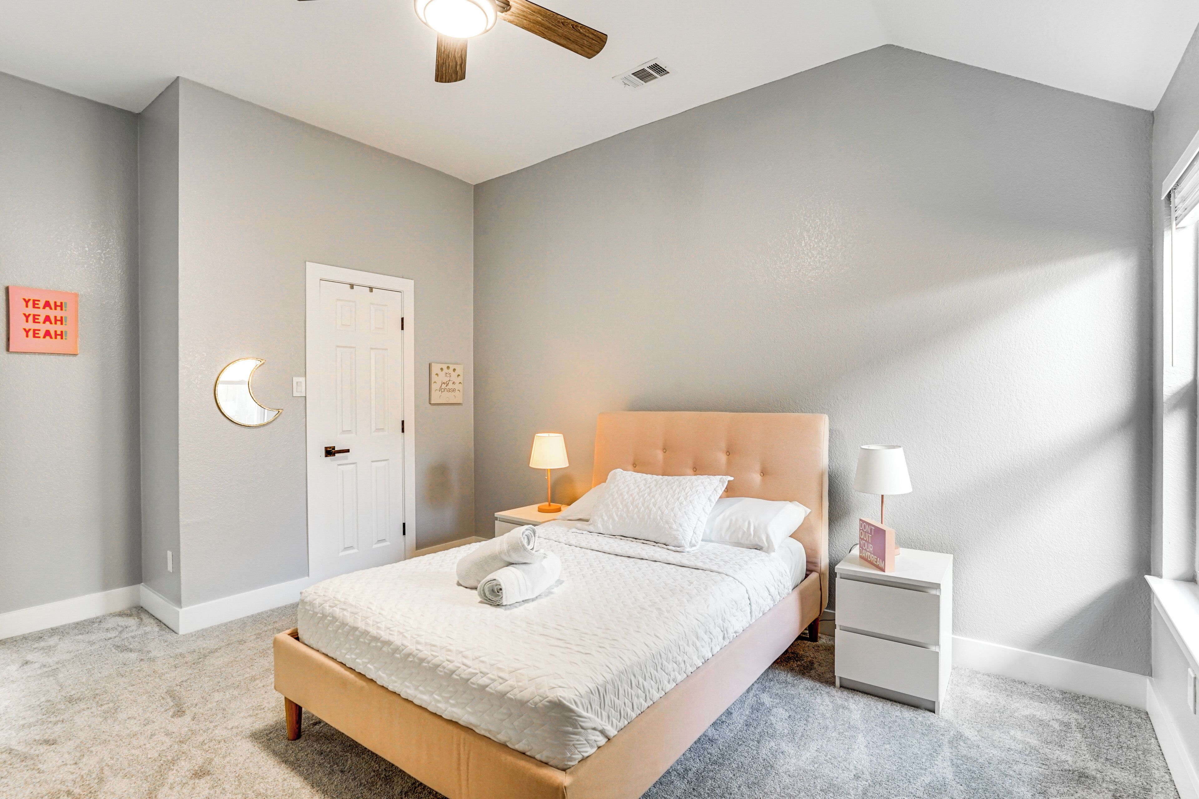 Una camera da letto con un letto, comodini, una ventola a soffitto e una porta.