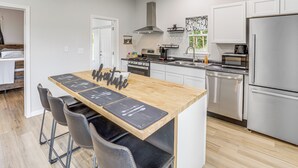 Una cocina moderna con una isla central, electrodomésticos de acero inoxidable y una zona de comedor con taburetes de bar.