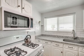 A modern kitchen with white cabinetry, a stainless steel sink, and a window with blinds. - El Paso Home ~ 2 Mi to University Medical Center! (El Paso)