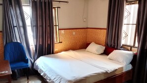 Una habitación de hotel con una cama grande, una silla azul y un cabecero de madera.