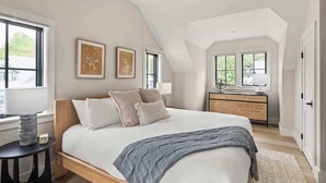 Ein Schlafzimmer mit einem großen Bett, einem Schminktisch und zwei Fenstern.